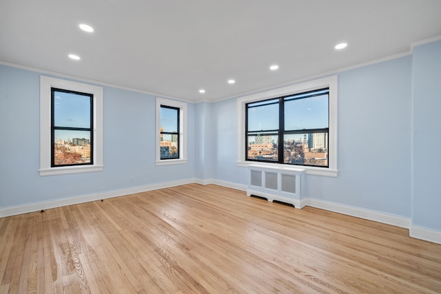 unfurnished room featuring crown molding, radiator heating unit, and light hardwood / wood-style floors