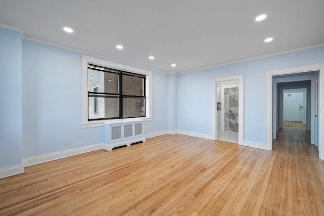 empty room featuring light wood-type flooring, ornamental molding, and radiator