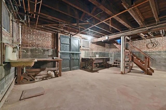 unfinished below grade area with brick wall, stairs, and a sink