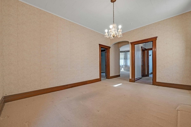 carpeted empty room with baseboards, arched walkways, crown molding, and wallpapered walls