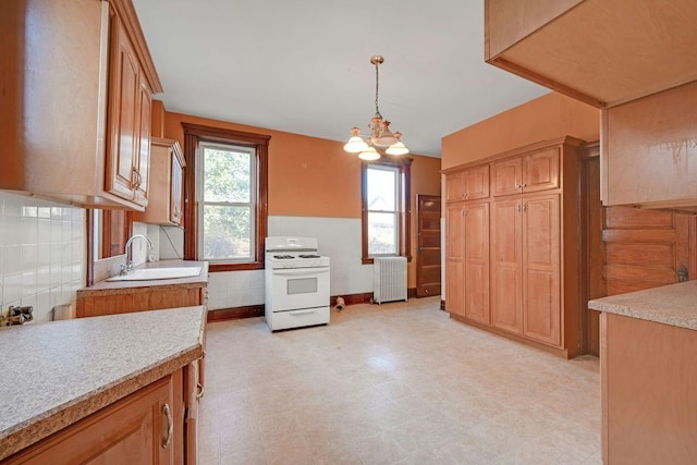 kitchen featuring pendant lighting, a sink, radiator, light countertops, and white range with gas stovetop