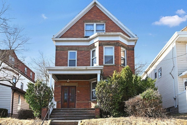 view of front facade with french doors, brick siding, and a porch