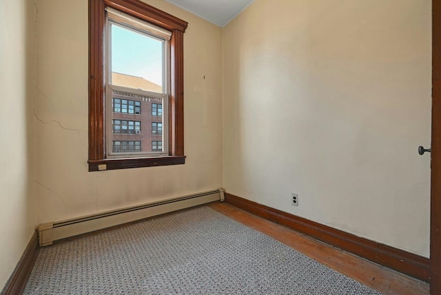 spare room featuring a baseboard heating unit and baseboards