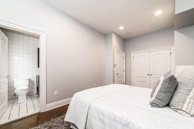 bedroom featuring connected bathroom, a closet, and dark wood-type flooring