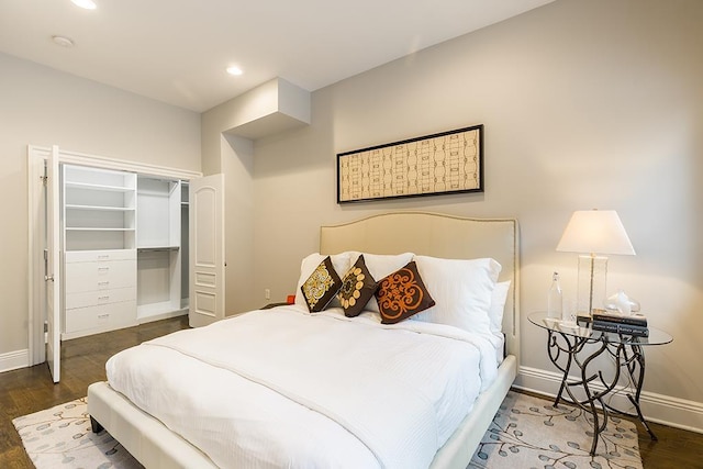 bedroom with a spacious closet, a closet, and dark hardwood / wood-style floors