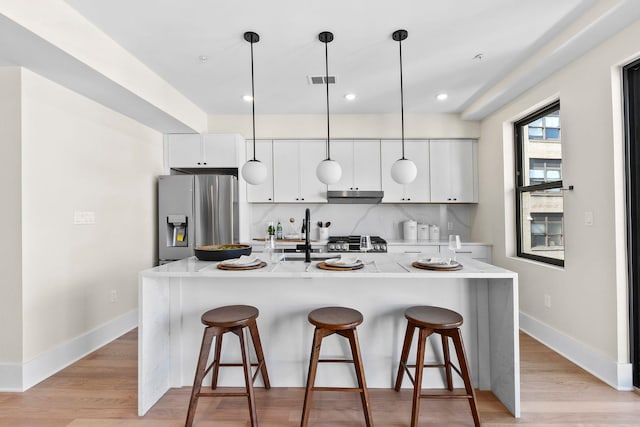 249 Bergen Ave Unit 201, Jersey City, NJ 07304 - kitchen featuring stainless steel refrigerator with ice dispenser, a breakfast bar, white cabinets, light wood finished floors, and a sink