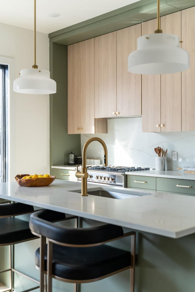 kitchen with light brown cabinetry, a breakfast bar area, decorative backsplash, hanging light fixtures, and modern cabinets