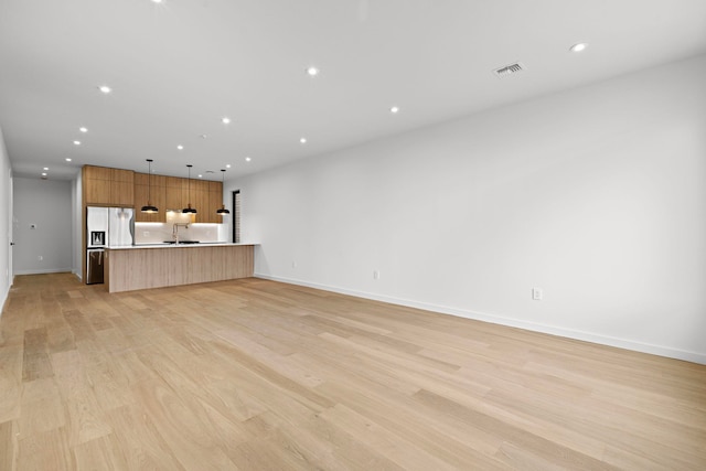 unfurnished living room featuring light wood finished floors, baseboards, visible vents, and recessed lighting