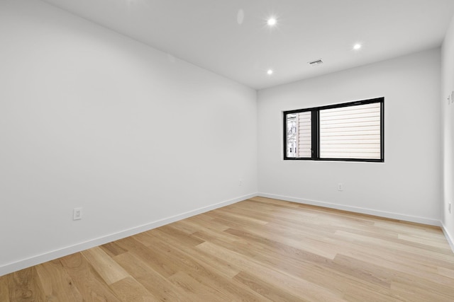 spare room featuring light wood-type flooring, visible vents, baseboards, and recessed lighting