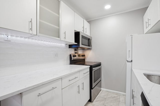 kitchen featuring stainless steel appliances, white cabinets, light stone counters, and decorative backsplash