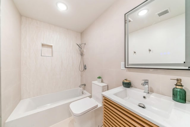 full bathroom with tiled shower / bath combo, vanity, tile walls, and toilet