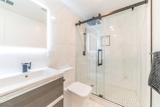 bathroom featuring tile walls, vanity, a shower with shower door, and toilet