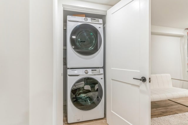 laundry room with stacked washer / drying machine and light wood-type flooring