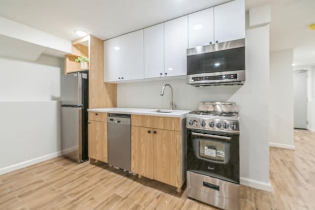 kitchen featuring stainless steel appliances, white cabinetry, sink, and light hardwood / wood-style flooring