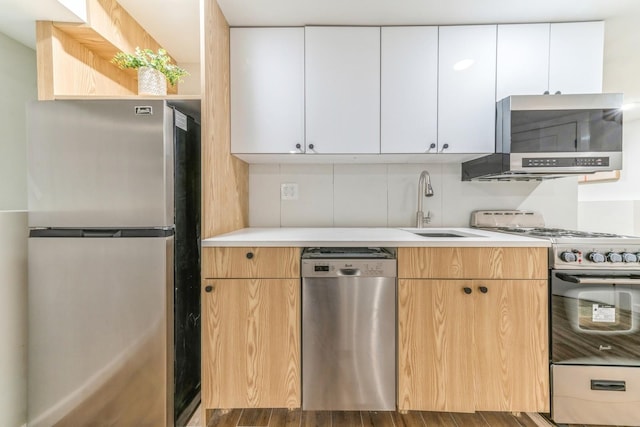 kitchen with appliances with stainless steel finishes, extractor fan, sink, and white cabinets