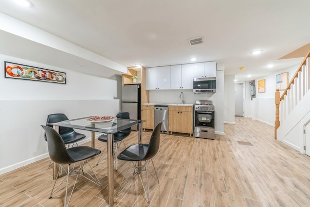 dining space featuring sink and light wood-type flooring