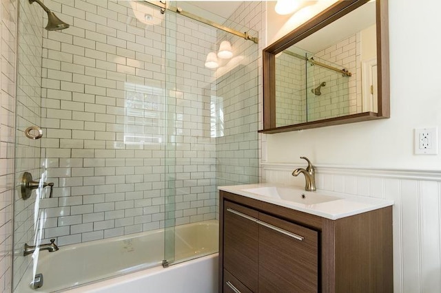 bathroom featuring enclosed tub / shower combo, wainscoting, and vanity