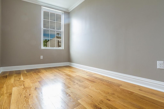 empty room featuring baseboards, light wood finished floors, and crown molding