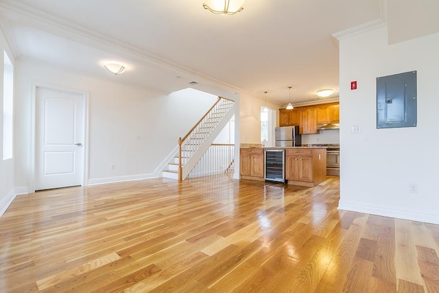 unfurnished living room featuring beverage cooler, electric panel, crown molding, and stairway