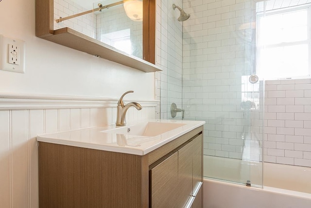 bathroom featuring a wainscoted wall, bath / shower combo with glass door, and vanity