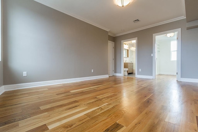 interior space featuring baseboards, light wood finished floors, and crown molding