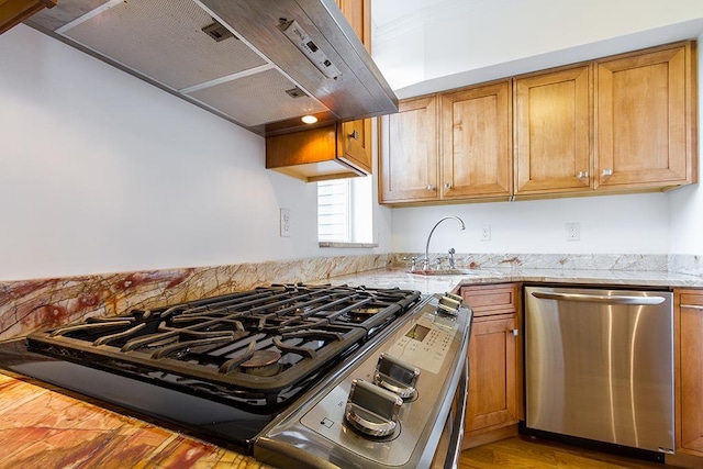 kitchen with light stone countertops, under cabinet range hood, brown cabinets, and stainless steel appliances