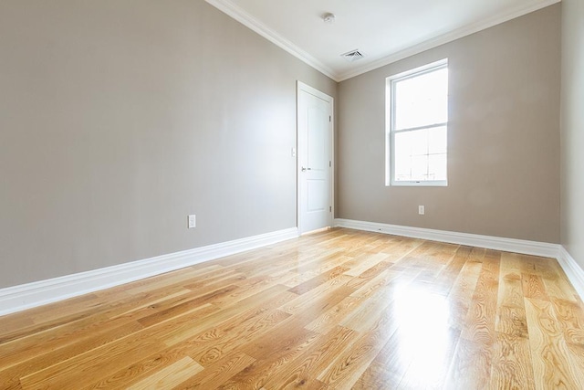 unfurnished room with light wood-style flooring, visible vents, ornamental molding, and baseboards