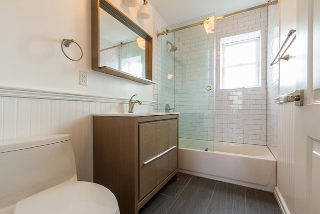 full bath featuring washtub / shower combination, wainscoting, vanity, and toilet