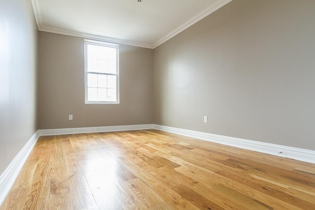 spare room featuring crown molding, light wood-style flooring, and baseboards