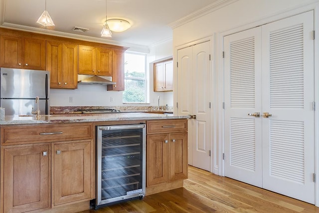 kitchen featuring stainless steel appliances, visible vents, ornamental molding, beverage cooler, and under cabinet range hood