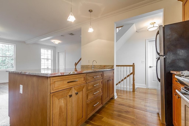 kitchen with appliances with stainless steel finishes, light stone counters, wood finished floors, and ornamental molding