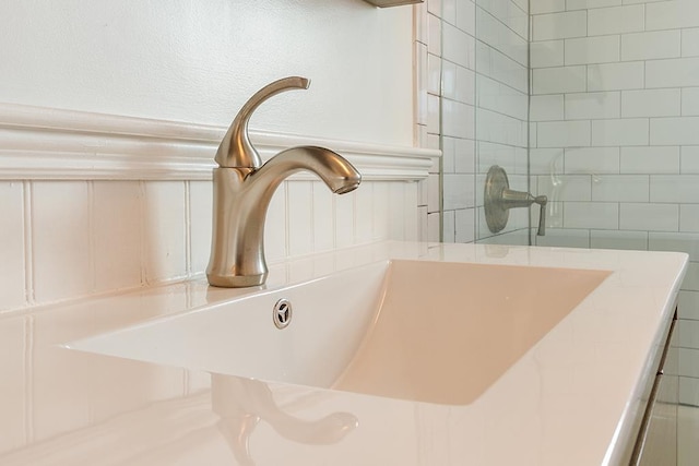 interior details with a tile shower and a sink