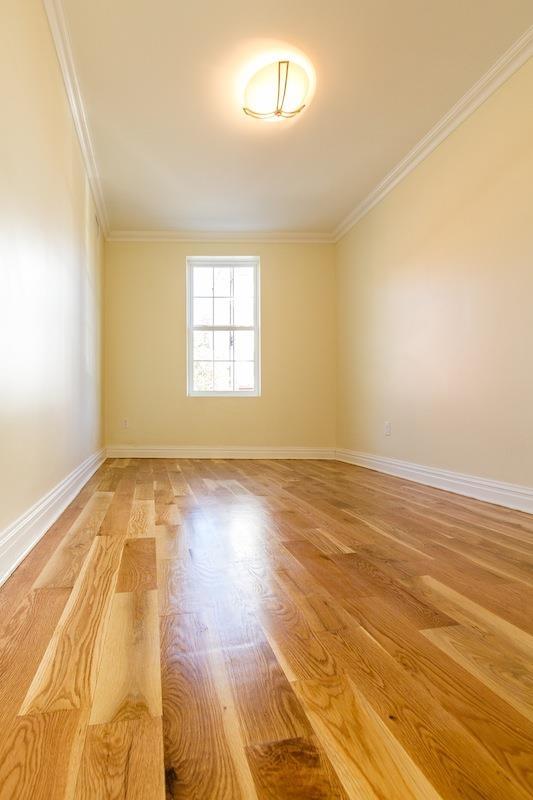 empty room with baseboards, ornamental molding, and light wood-style floors