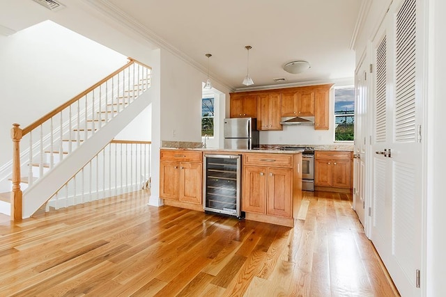 kitchen with wine cooler, light wood finished floors, appliances with stainless steel finishes, ornamental molding, and under cabinet range hood