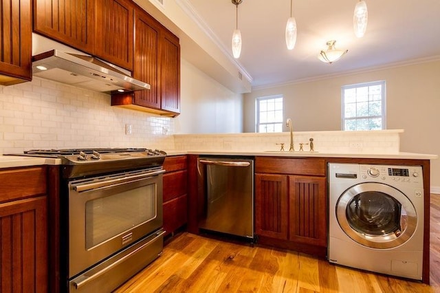 kitchen featuring under cabinet range hood, a sink, appliances with stainless steel finishes, washer / clothes dryer, and crown molding