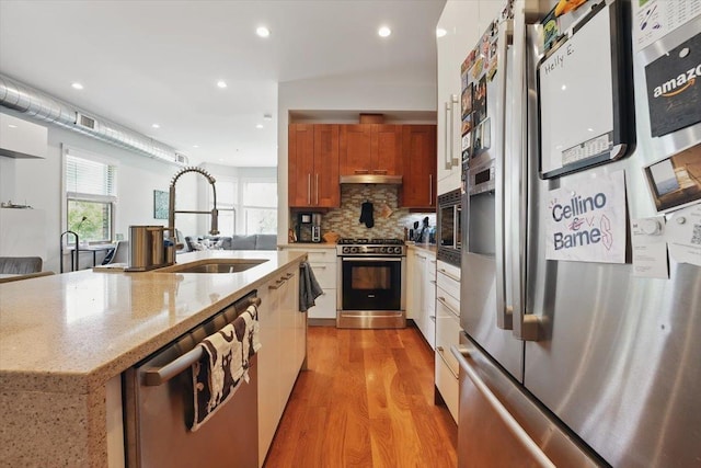 390 1st St Unit 2, Jersey City, NJ 07302 - kitchen featuring stainless steel appliances, a sink, brown cabinets, light wood-style flooring, and under cabinet range hood