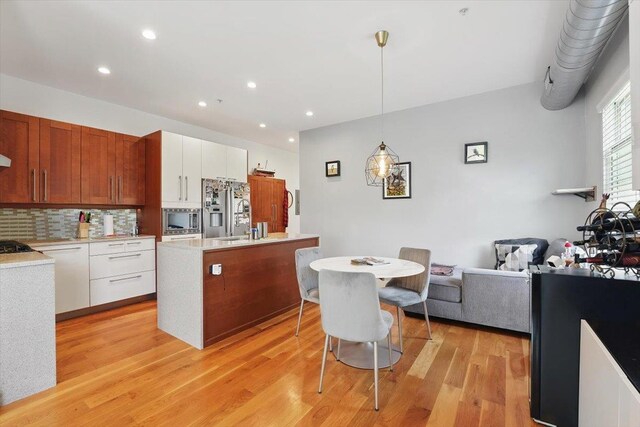 390 1st St Unit 2, Jersey City, NJ 07302 - kitchen featuring appliances with stainless steel finishes, light countertops, light wood finished floors, tasteful backsplash, and a kitchen island with sink