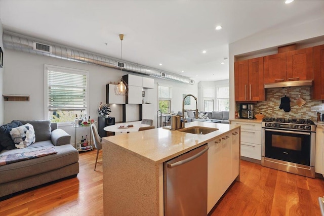 390 1st St Unit 2, Jersey City, NJ 07302 - kitchen featuring stainless steel appliances, open floor plan, a sink, light wood-style floors, and decorative backsplash