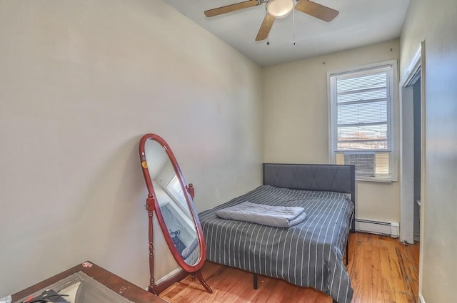 bedroom featuring a baseboard radiator, wood finished floors, and ceiling fan