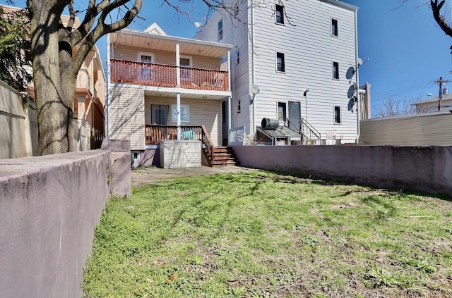 back of house with fence, a lawn, and a balcony