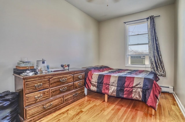 bedroom with cooling unit, wood finished floors, a baseboard heating unit, and a ceiling fan