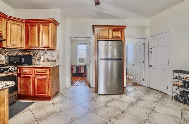 kitchen with tasteful backsplash, light tile patterned floors, light stone counters, and appliances with stainless steel finishes
