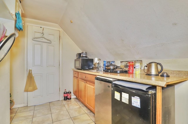 kitchen featuring black microwave, light tile patterned floors, light countertops, lofted ceiling, and fridge
