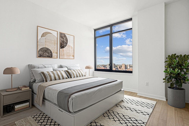 bedroom featuring floor to ceiling windows and light hardwood / wood-style flooring