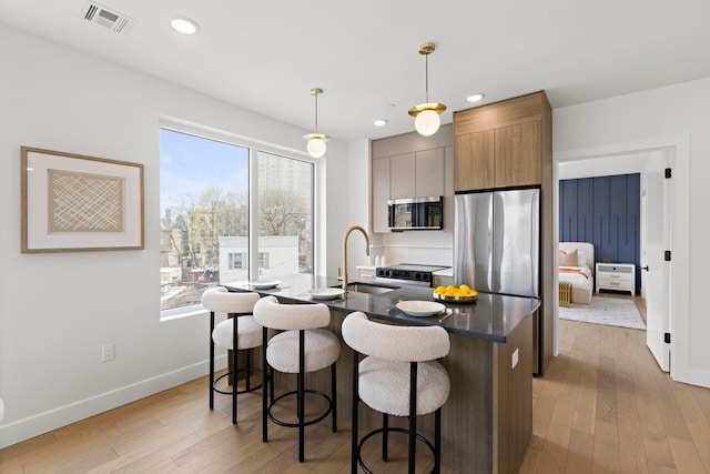 35 Orchard St Unit 301, Jersey City, NJ 07306 - kitchen with a kitchen breakfast bar, visible vents, a sink, stainless steel appliances, and light wood-style flooring