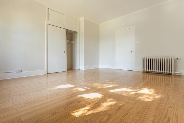 12 W 31st St, Bayonne, NJ 07002 - unfurnished bedroom featuring radiator heating unit, light wood-style floors, a closet, baseboards, and crown molding