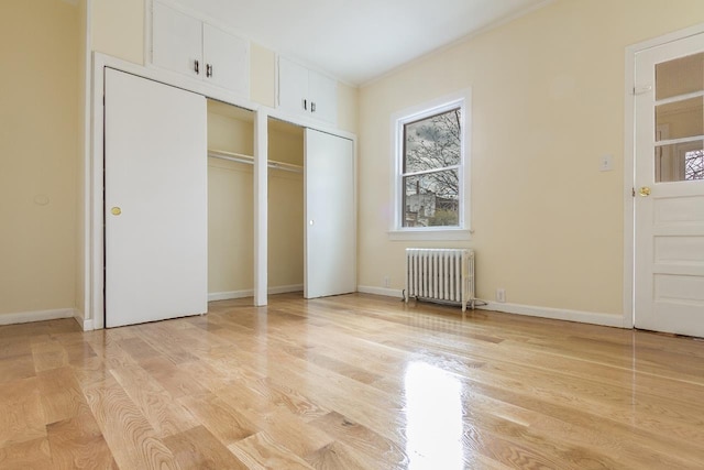 12 W 31st St, Bayonne, NJ 07002 - unfurnished bedroom with radiator, multiple closets, light wood-style floors, ornamental molding, and baseboards