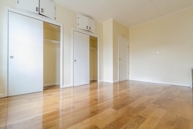 12 W 31st St, Bayonne, NJ 07002 - unfurnished bedroom with light wood-style flooring, two closets, and baseboards