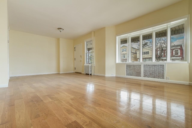 12 W 31st St, Bayonne, NJ 07002 - empty room with radiator, light wood-style floors, and baseboards