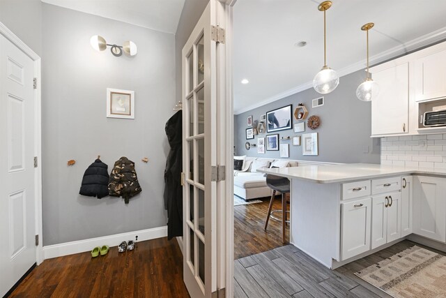 4 Sherman Ave Unit 1, Jersey City, NJ 07307 - kitchen featuring wood finished floors, a peninsula, white cabinets, decorative backsplash, and a breakfast bar